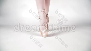 美丽的腿芭蕾舞演员在黑角的白色背景，特写。 古典舞芭蕾。 慢动作